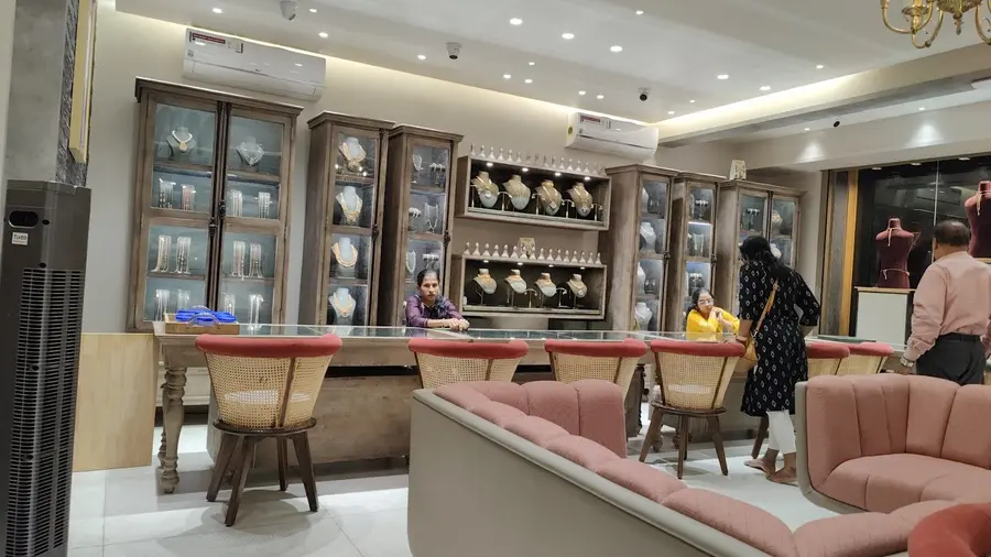 The ground-floor counter: pale wood and glass cabinets with white busts, cane-backed chairs and pink upholstered seats.