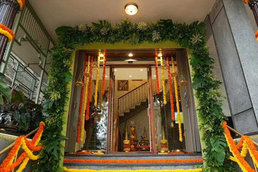 The entrance hung with marigold and mango-leaf festoons, a wooden staircase visible through the glass doors.