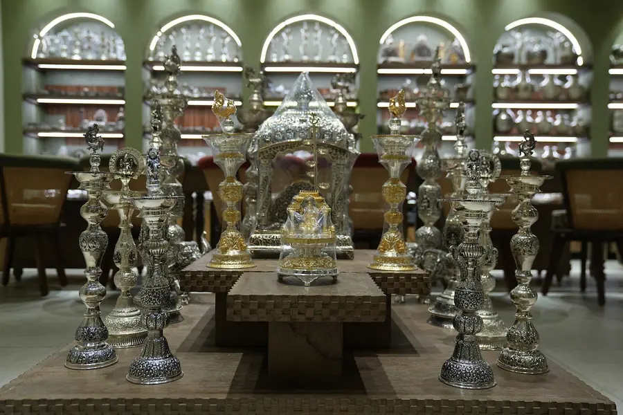 The silver room: rows of silver lamps, kalash and temple mantapas on wooden plinths under lit arched niches.