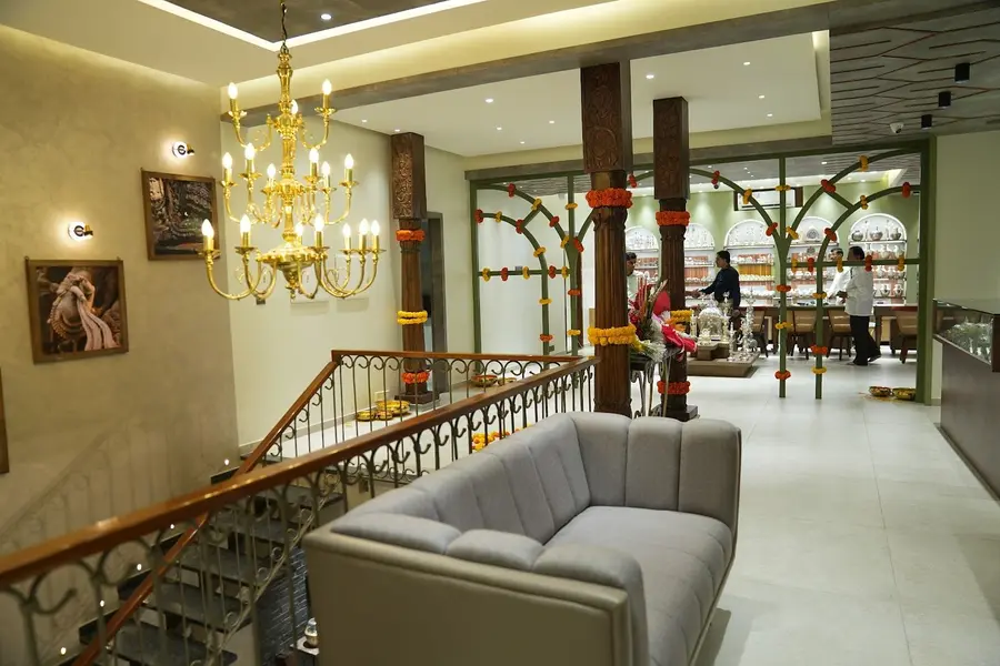 The upper floor: a gold chandelier, wooden pillars wound with marigold, a grey sofa on a mezzanine overlooking the shop.